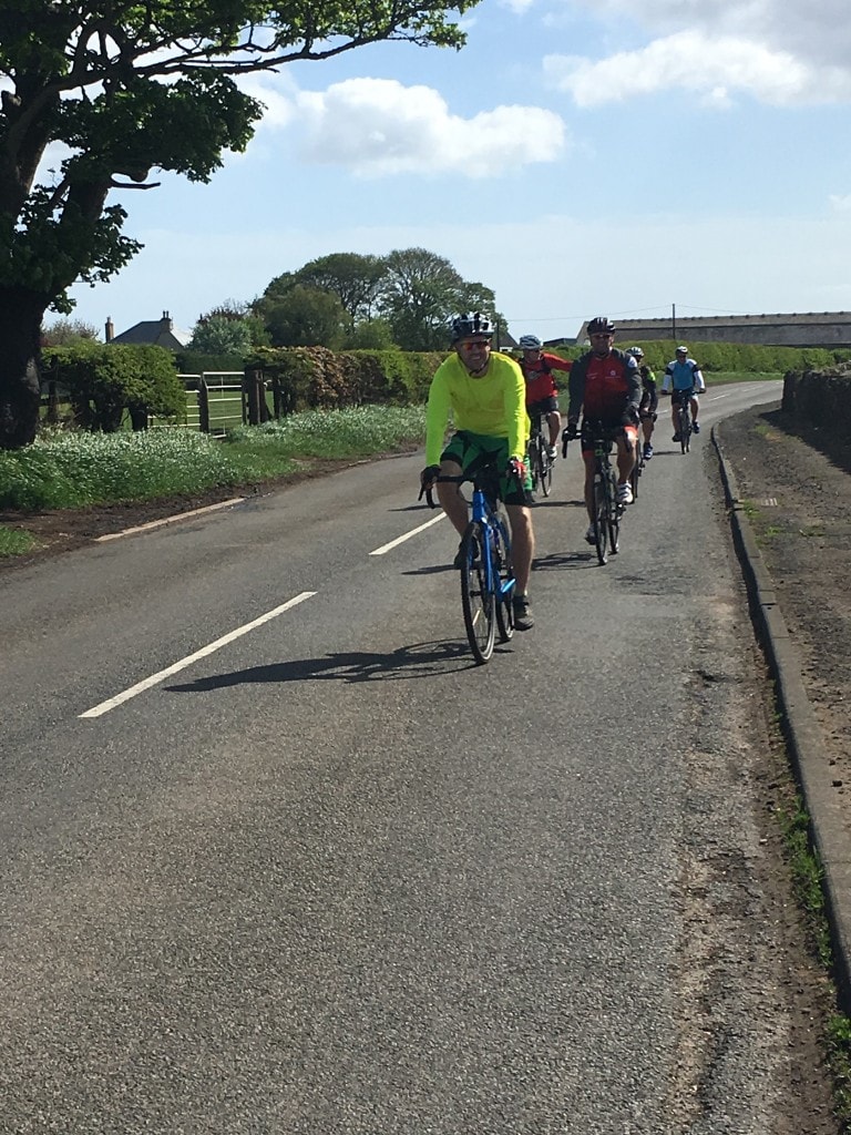 Group of cyclists riding along road on coast and castles cycleway